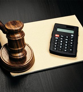 Wooden judge's gavel and calculator on table